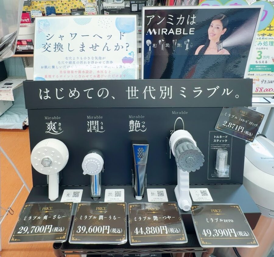 ミラブルシャワーヘッドの展示。黒い高級感のある展示台に置いているのは世代別、使用別にオススメしている４種類のシャワーヘッド。そしてそれに使用するフィルターも置いてある。広告宣伝は芸能人のアンミカ。