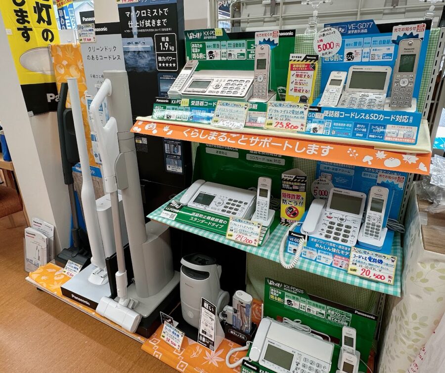 左側には年末に向けての掃除機が展示。今人気のコードレス掃除機が3台。内1台はゴミが掃除機のスタンドに移動し紙パックで捨てられるもの。手前は迷惑電話防止機能付きの電話機やFAX機を種類別に計5台展示。小山市では65歳以上の方に補助金がでる。